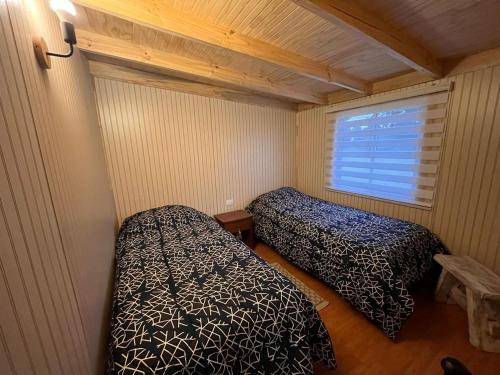 FreireCabañas Los Maitenes的小房间设有两张床和窗户