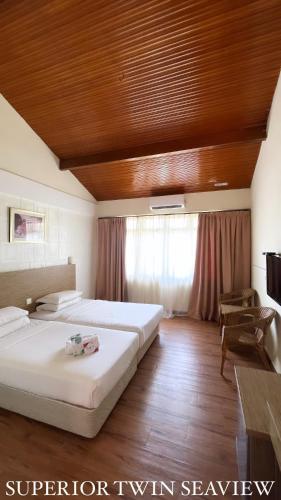 马六甲Lovita Tanjung Bidara Beach Resort的一间卧室设有两张床和木制天花板