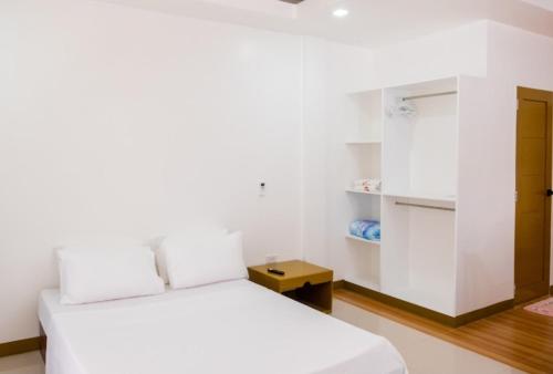 杜马格特E and C tourist inn的一间白色卧室,配有两张床和一个衣柜