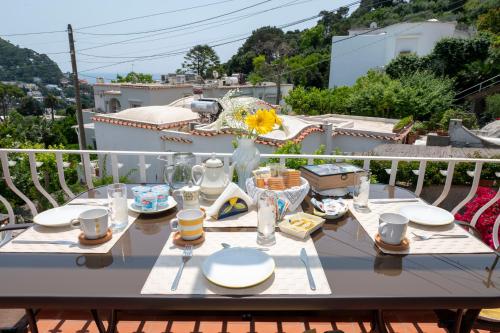 卡普里Casa Rubina的阳台上的桌子上摆放着盘子和玻璃杯