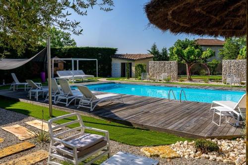 Saint-Paul-lès-Romans卡琳酒店的游泳池旁设有椅子和木甲板