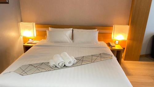 武里南Buritel Hotel的卧室配有带两盏灯的白色床