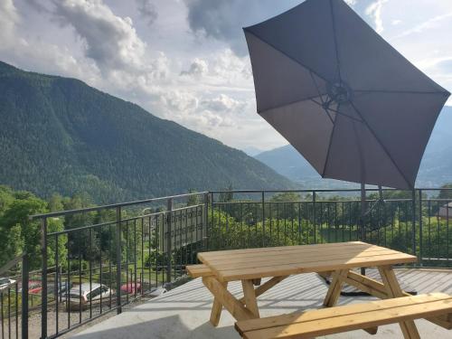 斯姿Location Paradiski San Bernardo的一张木凳,坐在带雨伞的阳台