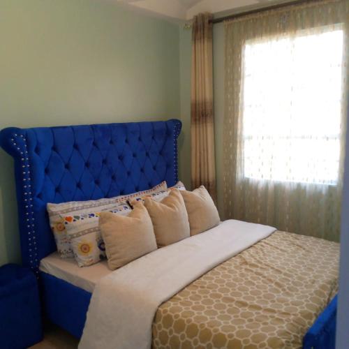 ThikaVerona Airbnb的一张带蓝色床头板和窗户的床