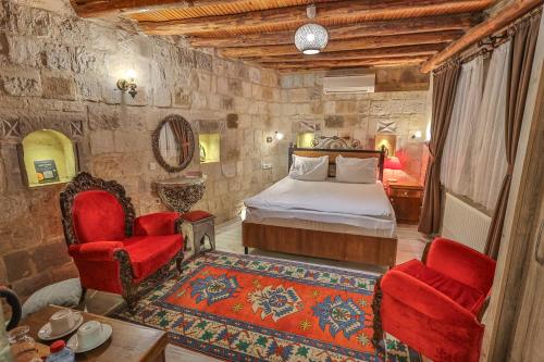 格雷梅基岩窑洞酒店的一间卧室配有一张床和两张红色椅子