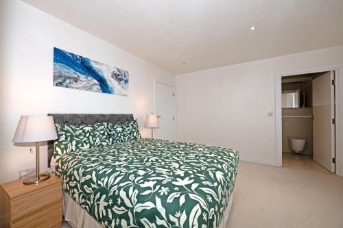 伦敦伦敦市中心舒适公寓的一间卧室配有一张带绿色和白色床单的床。