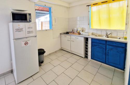 拜马欧appartement T2 avec jacuzzi的厨房配有白色冰箱和蓝色橱柜