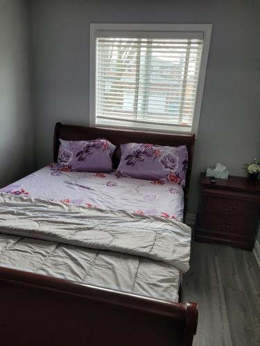 布兰普顿Individual home的一间卧室配有一张带紫色枕头的床和窗户。