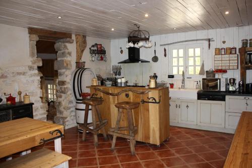FrontenaudLE DOMAINE DU SENS的厨房配有白色橱柜和带凳子的台面