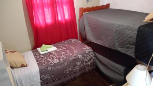 特尔马斯德里奥翁多Cabaña La Solanita的一间小卧室,配有两张床和红色窗帘