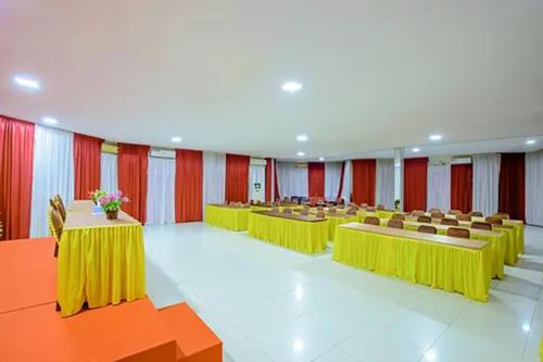 TebingtinggiMalibou Hotel的一间会议室,配有黄色的桌椅和红色的窗帘