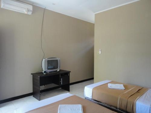 圣吉吉帕库纳海滩酒店的客房设有两张床和一张桌子上的电视