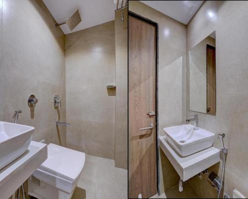 孟买Atithi Int'l-International Airport的浴室设有2个盥洗盆、淋浴和镜子。