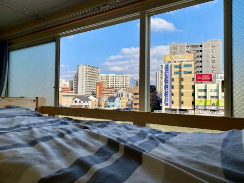 福冈Fukuoka Tabiji Hostel & Guesthouse的卧室设有窗户,享有城市美景