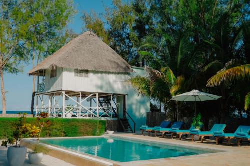 江比阿Villa Passiflora Zanzibar的一座带椅子和遮阳伞的游泳池以及一座建筑
