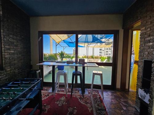 蒙得维的亚Montevideo Hostel的厨房配有带凳子的桌子和大窗户