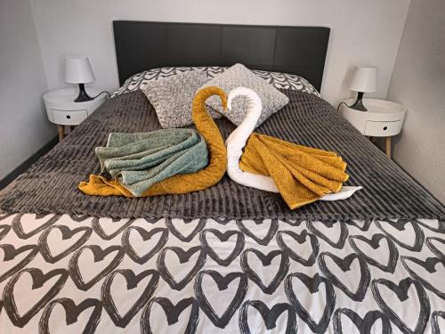乐巴凯尔斯Chez Fifi au Barcarès的一张带两条毛巾和天鹅的床