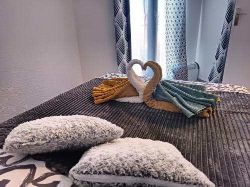乐巴凯尔斯Chez Fifi au Barcarès的一张带两个枕头的床和一个天鹅