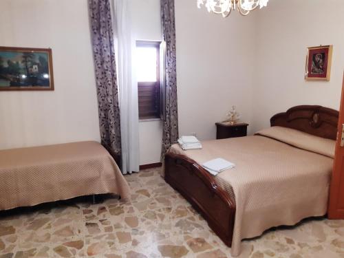 MilenaLa casa di Lina的一间卧室设有两张床、一个窗户和一个吊灯。