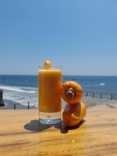 圣米格尔Kuluka Resort And Spa的坐在海滩边的桌子上喝一杯橙汁