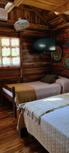 普拉亚埃尔莫萨Congos Hostal y Camping的一间卧室配有两张床和一台平面电视