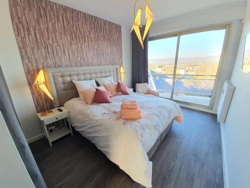 埃佩尔奈L'épopée Panoramique - Parking - Avenue de Champagne - Epernay的一间卧室配有带粉红色枕头的床和窗户。