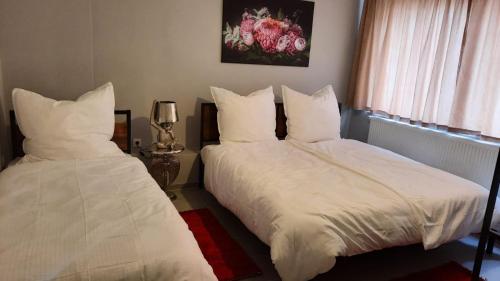 科隆Niehler Hotel的一间卧室设有两张带白色床单的床和窗户。