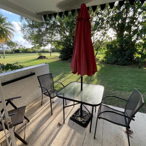 布里奇敦Studio apartment in heart of south coast Barbados的露台上的一张桌子和一把红色遮阳伞
