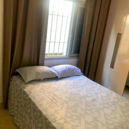 索莱马Recanto Caiçara的一间卧室配有带两个枕头的床和窗户
