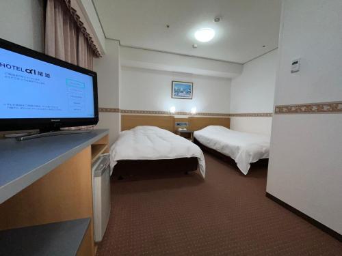 尾道市Hotel Alpha-One Onomichi的酒店客房设有两张床和一台平面电视。