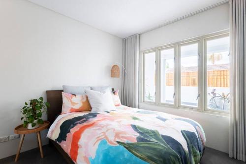 悉尼Balmain Designer 1 Bedroom Apartment with Parking的一间卧室配有一张带五颜六色的被子的床和窗户