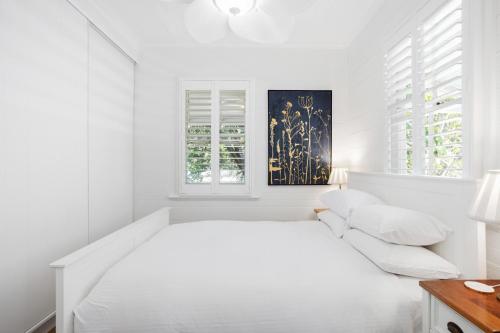布里斯班Tranquil 2-Bed Family Home with Deck Among Trees的白色的卧室设有白色的床和窗户。