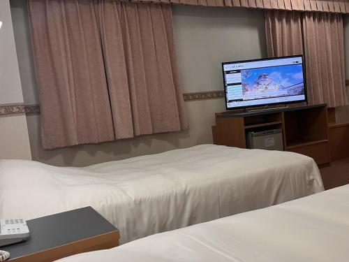 会津若松Hotel Alpha-One Aizuwakamatsu的酒店客房设有两张床和一台平面电视。