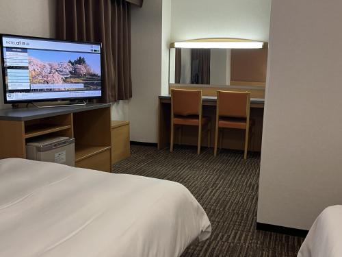 郡山Hotel Alpha-One Koriyama的酒店客房配有一张床和一张书桌及一台电视