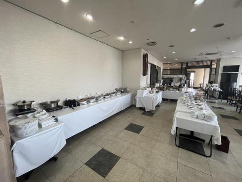 鹤冈市Hotel Alpha-One Tsuruoka的一间用餐室,配有白色的桌子和白色的菜肴