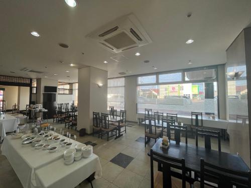 鹤冈市Hotel Alpha-One Tsuruoka的一间设有白色桌椅和窗户的用餐室