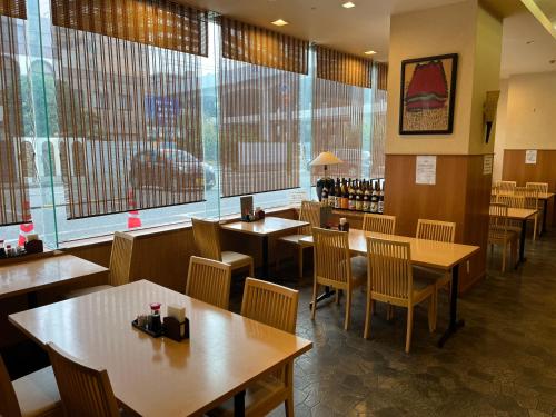 新泻Hotel Alpha-One Niigata的餐厅设有木桌、椅子和窗户。