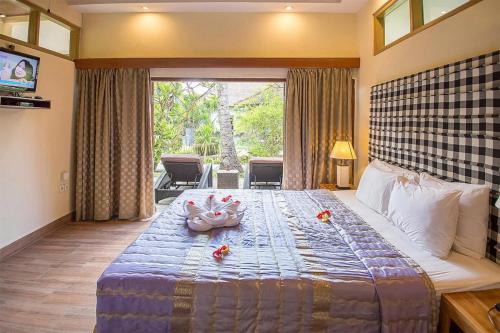 甘地达萨湾畔简易别墅酒店的一间卧室配有一张带鲜花的大床