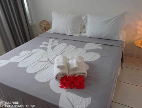 帕皮提Manaeva L3的一张带毛巾和红色鲜花的床