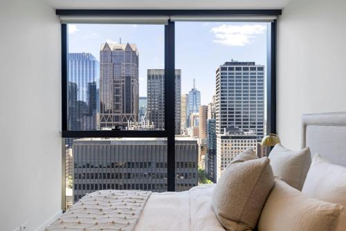 墨尔本Luxuria Apartments - Collins House的一间卧室设有大窗户,享有城市景观