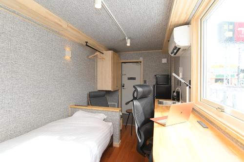 千岁JR Mobile Inn Chitose的客房设有一张床、一张桌子和一台笔记本电脑