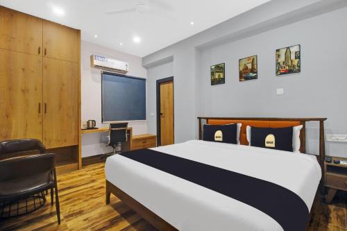 海得拉巴Townhouse Hitec City Near Image Hospital的一间卧室配有一张床、一张书桌和一台电视。