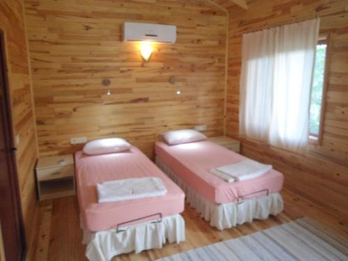 契拉勒Bungalow Halil的木墙客房内的两张粉红色床铺