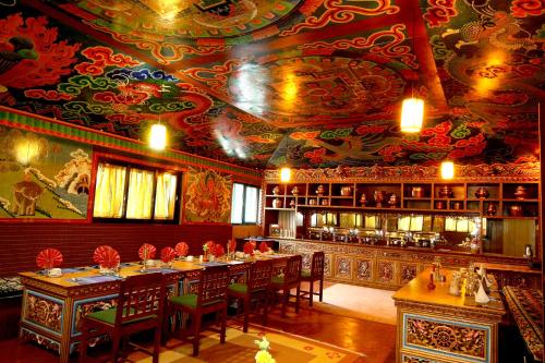LuklaMountain Lodges of Nepal - Lukla的用餐室配有带椅子的长桌和带绘画的天花板
