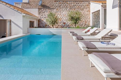 杜布罗夫尼克Brand New Villa Carmelita Exclusive with free Smart Car的一个带躺椅的游泳池和一个游泳池