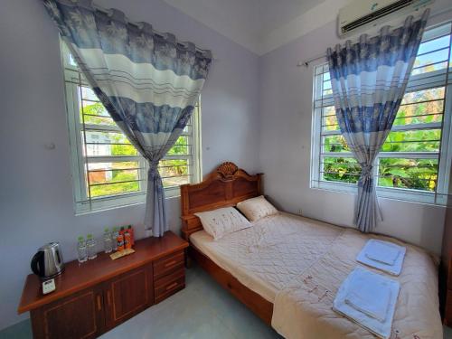Xóm MũiVườn Quốc Gia U Minh Hạ的一间卧室设有一张床和两个窗户。