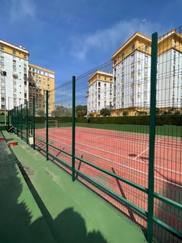 塞维利亚Magnífico Apartamento en Sevilla的一座网球场,有两栋建筑背景