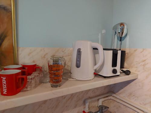 PožegaKuca - STUDIO的厨房架上配有烤面包机和杯子