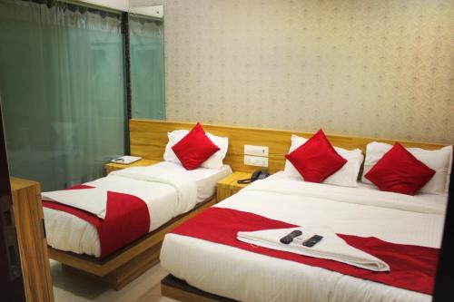 孟买MAROL METRO HOTEL MUMBAI的两张位于酒店客房的床,配有红色和白色枕头