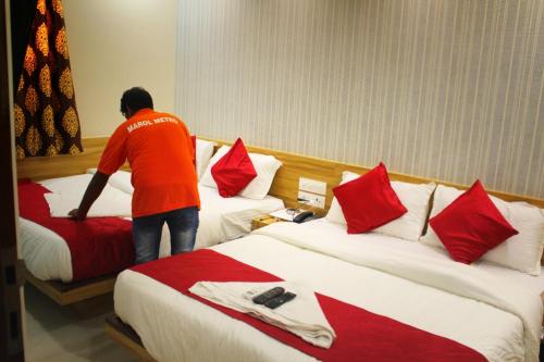 孟买MAROL METRO HOTEL MUMBAI的站在酒店房间两张床之间的男人